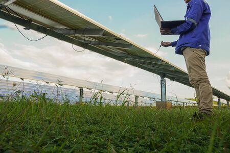 The low angle view of the solar farm and the engineers are using the computer to check the operation...