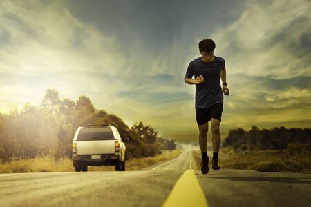 Low-angle shots of runners running on the street in the evening with orange sunlight, the concept of...