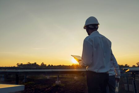 The solar farm(solar panel) with engineers walk to check the operation of the system by tablet,...