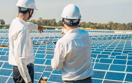 The solar farm(solar panel) with two engineers are talk about the production capacity, Alternative energy to conserve the world's energy, Photovoltaic module idea for clean energy production.