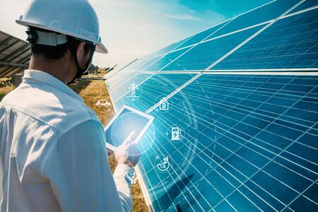 The solar farm(solar panel) with engineers walk to check the operation of the system by laptop,...