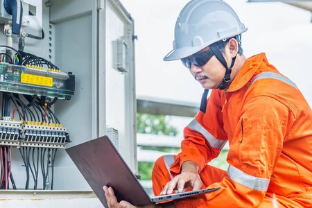Engineers upload data of power energy to a laptop for checking the performance of the solar panel to...