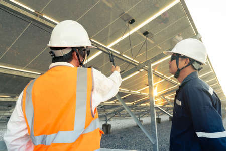 Technician with engineer checks the connection of the solar panels in the solar plant, Alternative energy to conserve the world's energy, Photovoltaic module idea for clean energy production.の写真素材
