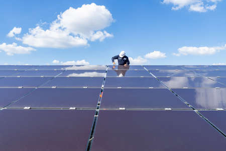The solar farm with the technician is removing the nut to replace the damaged solar panel,...
