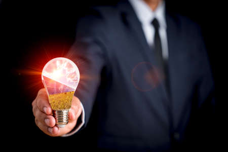 à¸ºBusinessman holds a light bulb with a picture of sunlight and a solar cell inside the light bulb. Alternative energy to conserve world energy. Photovoltaic module idea for clean energy production.の写真素材
