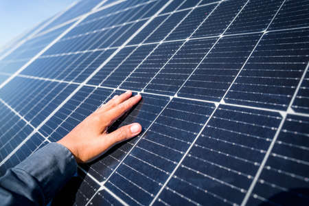Man hand touching the solar panel, hot climate causes increased power production, Alternative energy...