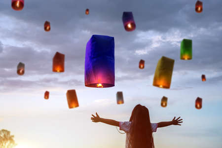 Asian child girls are releasing lanterns to blessings from the Holy for happiness on the important Buddhist holy day it is Buddhist Lent days. Child girls stand and look with excitement.の写真素材