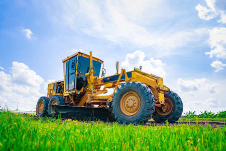 The ground grader is adjusting the road surface evenly to the level that engineers have calculated,...