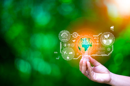 Net zero concept help reduce global warming.Hand holding natural background light bulb on green leaf with clean energy icon around it. Carbon dioxide emission in industry net zero carbon concept.の写真素材