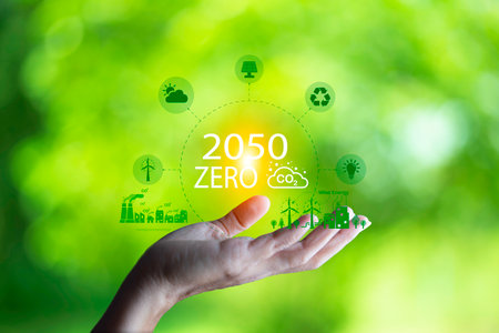 Hand holding with  green energy, Wind energy system icon on blur green leaf. Wind energy for eco car. carbon neutral and green natural background  with energy icon around it. Net zero 2050.の写真素材