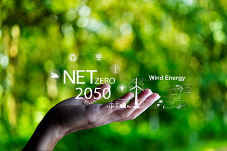 Hand holding with  green energy, Wind energy system icon on blur green leaf. Wind energy for eco car. carbon neutral and green natural background  with energy icon around it. Net zero 2050の写真素材