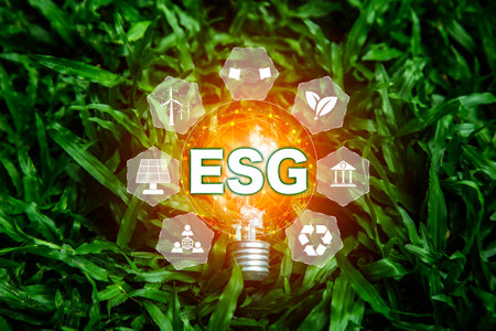 ESG icon in light bulb on green grass nature background. green energy, eco earth day concept. golden light in morning. icon energy and environmental protection around it. energy sources for renewableの写真素材