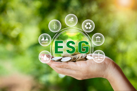 green energy concept. esg icon on pile of gold coins in hand on green nature background. Investing...