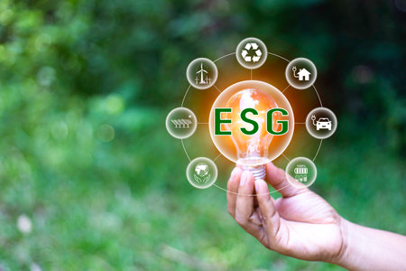 ESG icon in light bulb on green grass nature background. green energy, eco earth day concept. golden light in morning. icon energy and environmental protection around it. energy sources for renewableの写真素材
