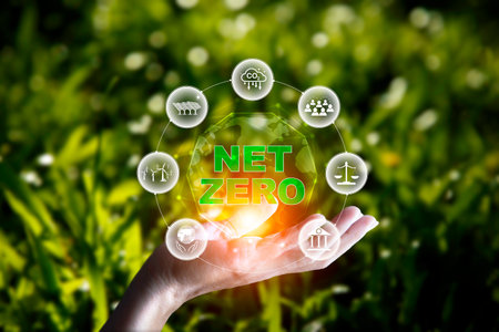 net zero concept. Hand holding with net zero icon on blur green leaf. carbon neutral and green natural background  on with clean energy icon around it. Carbon gas affects global warming.の写真素材