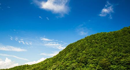 Beautiful mountain landscape, with mountain peaks covered with forest and a cloudy sky.の写真素材
