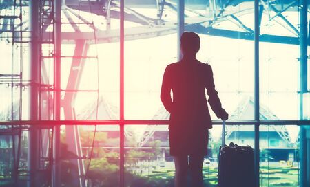 Young woman in international airport, checking her phone while waiting for her flightの写真素材