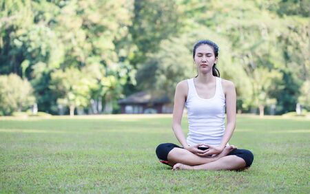Young woman doing yoga in morning parkの写真素材