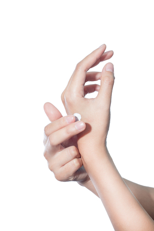 Asian woman isolated on white studio shot applying cream on her handsの写真素材