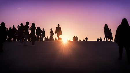 Silhouettes of group of people watching the sunset togetherの写真素材