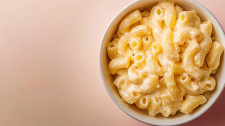 A top view of a bowl filled with creamy macaroni and cheese. The delectable dish showcases a rich, smooth texture against a soft pastel background, perfect for food photography.の素材
