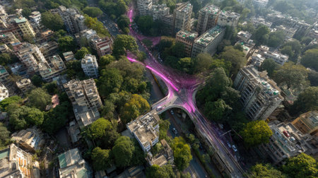 This vibrant aerial view showcases a busy urban intersection, adorned with pink light trails. The blend of greenery and architecture creates a dynamic city landscape.の素材