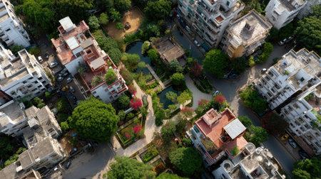 This aerial image captures a vibrant urban landscape featuring green parks, residential buildings, trees, and pathways in a lively city environment.の素材