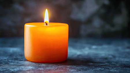 A single orange candle lit in darkness, symbolizing remembrance and awareness, with room for textの素材