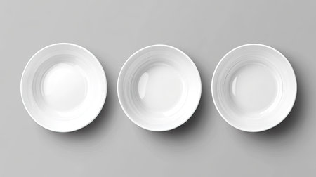 This image features three empty white plates arranged neatly on a gray background. Ideal for minimalist design, culinary presentations, or kitchen-related themes.の素材