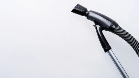 A sleek black vacuum cleaner hose with a nozzle against a plain background, showcasing modern design and cleaning technology for home use.の素材