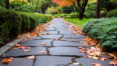 A picturesque stone pathway meanders through a lush garden, adorned with vibrant autumn leaves. The serene setting invites relaxation and exploration.の素材