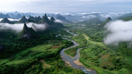 A stunning aerial image showcasing a lush green valley with a winding river, framed by majestic mountain peaks under a cloudy sky, perfect for nature themes.の素材