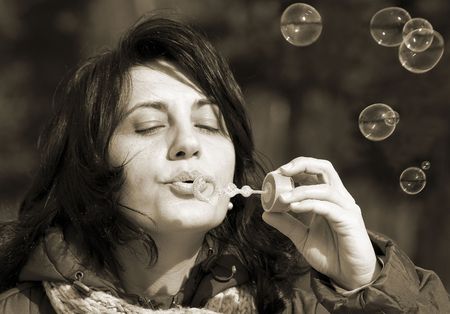 Young woman makes soap bubbles in park