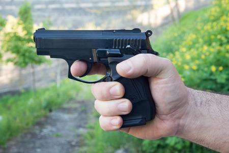 Detail of mans hand holding automatic pistol
