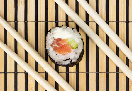 Sushi roll and chopsticks over bamboo matの写真素材