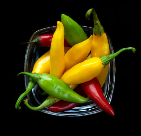 Chilies in glass cup on black backgroundの写真素材