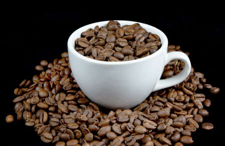 White cup arranged with coffee beans isolated on black backgroundの写真素材