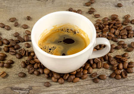 A cup of coffee and coffee beans on wooden boardの写真素材
