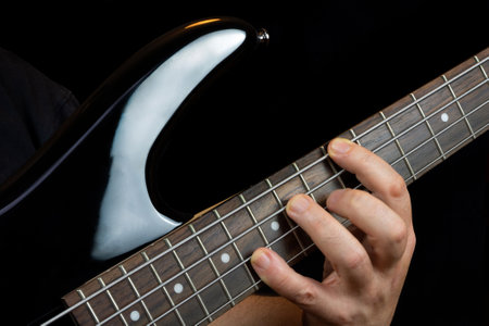 Guitarists hand playing on the fretboard of an electric bass guitarの写真素材