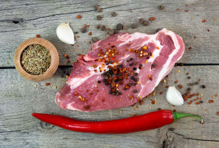 Raw meat steaks with spices on the wooden boardの写真素材