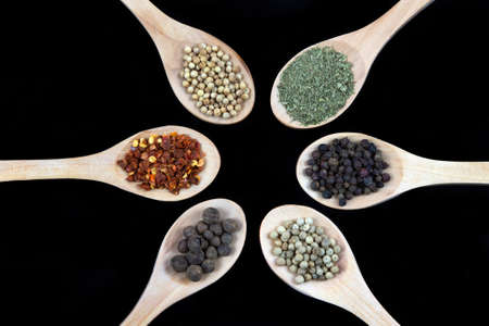 Spices in wooden spoon isolated on black backgroundの写真素材