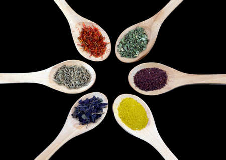 Spices in wooden spoon isolated on black backgroundの写真素材