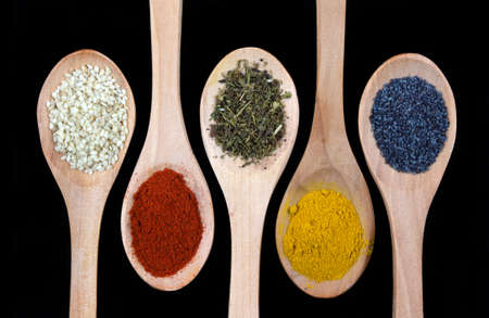 Spices in wooden spoon isolated on black backgroundの写真素材