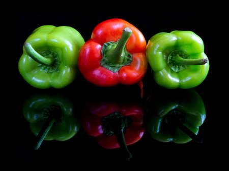 Red and green pappers on black reflective studio backgroundの写真素材
