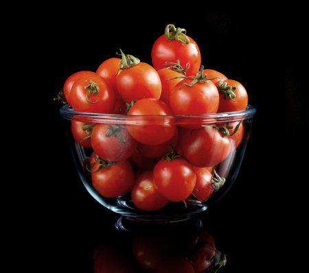 Cherry tomatoes on black reflective backgroundの写真素材