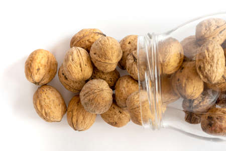 Whole solid walnuts in a jar on white backgroundの写真素材