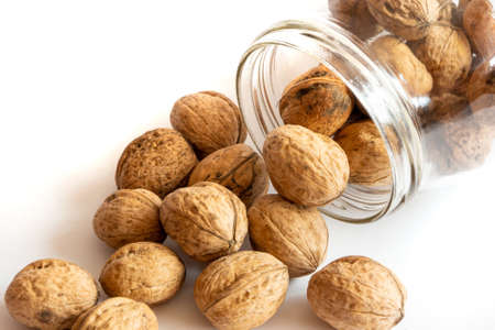 Whole solid walnuts in a jar on white backgroundの写真素材