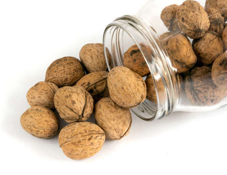 Whole solid walnuts in a jar on white backgroundの写真素材
