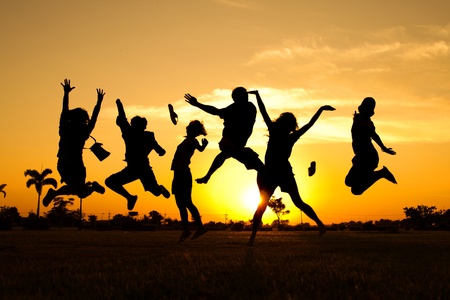 Teenagers jumping over sunsetの写真素材