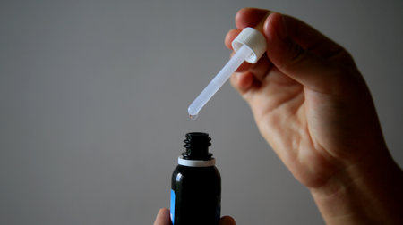 salvador, bahia / brazil - may 7, 2020: hand removes weak medication with the aid of a dropper.のeditorial素材
